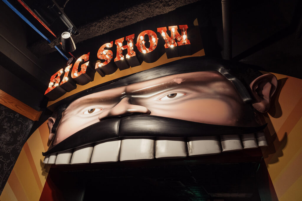 Theater entrance, designed to look like an open mouth with large teeth, a moustache, and text reading "The Big Show."