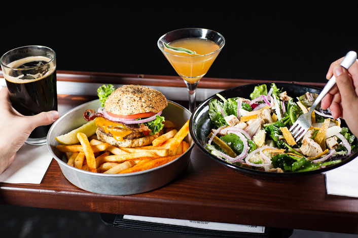 A delicious meal of fries, a large salad, and perfectly cooked hamburger with the works. To the side, a martini delicious martini and coke. (Lucky moviegoer!)