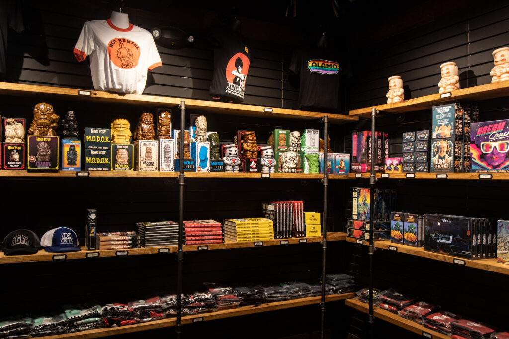 A dark corner featuring a mix of movie and Alamo merchandise, from shirts to candy.