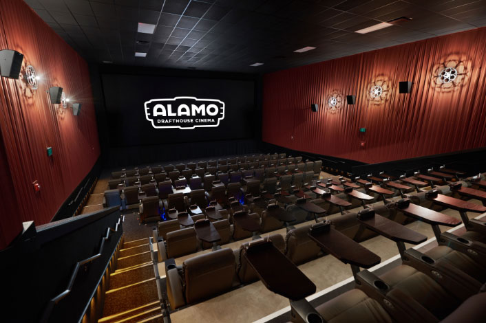 An empty theater, shot from the furthest back seats. The Alamo Drafthouse logo lit on the screen.
