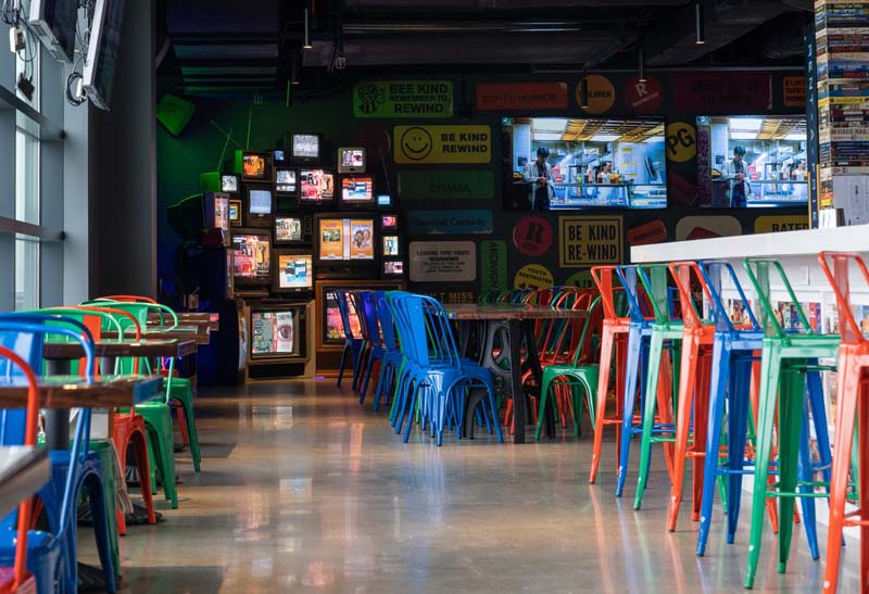 The Wriggleyville Alamo Drafthouse lobby is filled with multicolored bar stools and old classic television plastered on the wall.